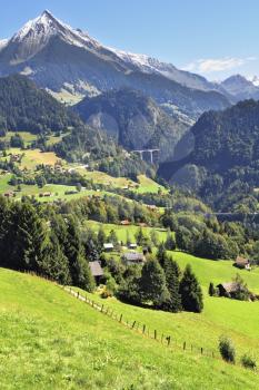 Gorgeous weather in the vicinity of the ski resort of Leysin in the Swiss Alps. The picturesque alpine meadows, rural houses chalets. Away bridges across the abyss and the majestic snow-capped mountai