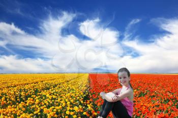 Charming smiling girl with a scythe in a field of blooming yellow and red buttercups