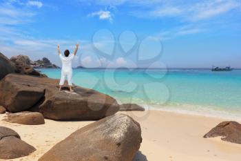  Middle-aged woman dressed in white doing yoga. Asana Blessing of the Sun. Thailand. Gorgeous beach on the Similan Islands.