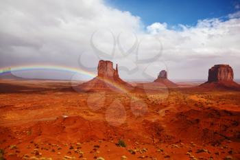 Red stone desert Navajo, USA. Isolated rocks - mitts intersect with the beautiful rainbow. On the road, the car is worth