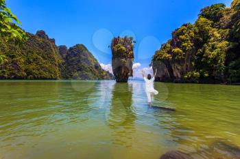 Woman performs yoga pose standing in the water of the Andaman Sea. Exotic vacation in Thailand