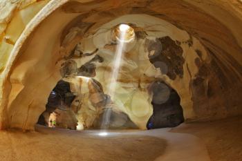 Famous belfry Beit Guvrin caves in Israel. Giant halls regular shape with a hole in the roof. Through an opening in the ceiling of the cave inside the sun's rays penetrate