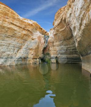 Unique canyon in the desert. Picturesque canyon En-Avdat in the Negev desert. Bowl waterfall reflects the sky. Sandstone canyon walls form round bowl