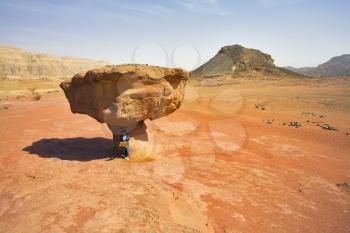 The lonely woman - tourist reads map near to a huge rock from red sandstone