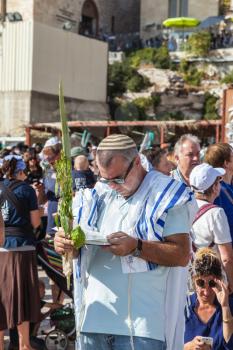 JERUSALEM, ISRAEL - OCTOBER 12, 2014: The area in front of the Western Wall of the Temple filled with people. Morning autumn Sukkot. Many brought prayer books and four ritual plants