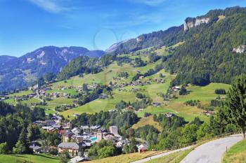 Swiss Alps. Alpine meadows on gentle slopes, green trees and a small village in the vicinity of the resort of Leysin