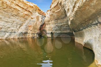 Unique canyon in the desert. Picturesque canyon Ein-Avdat in the Negev desert. Sandstone canyon walls form round bowl. Bowl waterfall reflects the sky