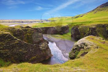 The picturesque canyon Fjadrargljufur, rocks with yellowed grass and blue water of the river. Neverland Iceland