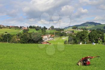 Green meadow with lush grass and red lawn mower. The charming rural landscape in Provence, France