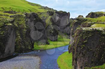 Iceland in the summer. Canyon Fjadrargljufur and cold fast river with a pebble bottom