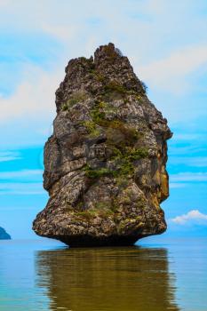 Island Sail in the ocean. The island is reflected in the smooth surface of the water. The blue haze of the warm sea - background for the huge stone cliff