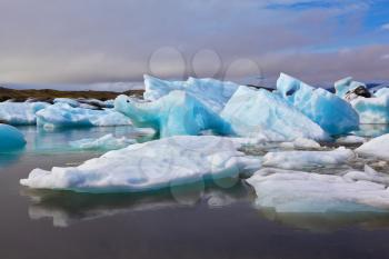 Sunrise. Blue and emerald icebergs and ice floes are reflected in smooth water of the Gulf Jökulsárlón in Iceland 