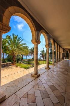 The basilica is surrounded by gallery with columns. Subtle shade of palms. Church Sermon on the Mount - Mount of Beatitudes