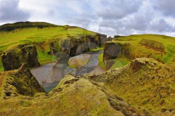 Neverland Iceland. Rocks with yellowed grass around the canyon  Fjadrargljufur