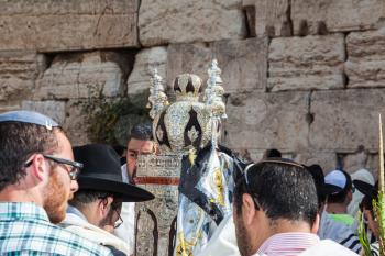 JERUSALEM, ISRAEL - OCTOBER 12, 2014: Morning autumn Sukkot. The area in front of Western Wall of  Temple. Crowd of Jewish worshipers in white wearing prayer shawls. On table there is Torah Roll in ma