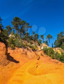 Steps for tourists on a steep slope. Unique red and orange hills in the province of Languedoc - Roussillon, France
