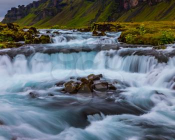 Powerful cascading waterfalls in Iceland. A wide picturesque valley along Highway 1 around the island. Travel in July. Concept of active and extreme tourism