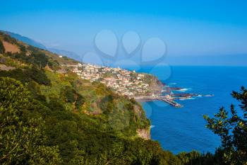 The magical tropical island of Madeira. The picturesque village with red tiled roofs on the cape is surrounded by forest. Concept of exotic and ecological tourism