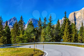  Southern Limestone Alps. Beautiful sunny day. The road passes in the coniferous forests at the foot of limestone and dolomite rocks. The concept of active and automobile tourism