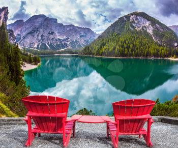 The concept of walking and eco-tourism. Two comfortable red deck chairs on the shore of the lake. Water reflects the surrounding mountains 
