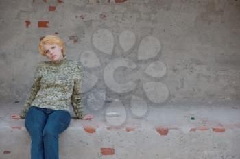 Blonde woman in a green sweater posing outdoors