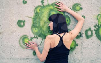 brunette girl posing against concrete wall with graffiti