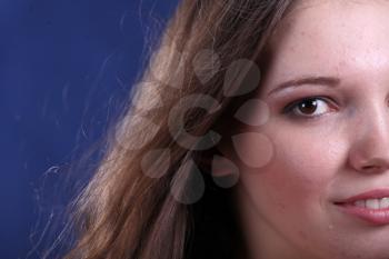 Studio portrait of a beautiful young brunette woman half face on blue