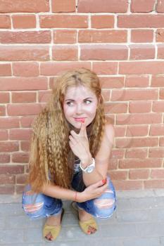 The girl with long hair sitting near wall looking playfully
