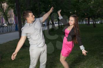 Happy young adult couple dancing outdoors at night, close-up