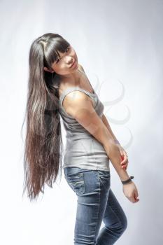 back view of standing young beautiful Asian woman in tank top and jeans torso shot. Teen watching. Rear view. Backside view of person. Shot over white background.