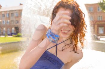 redhead women near fountain in summertime. Shot full og sunshine, Sunlit