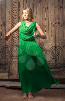 Full length romantic blond hair women in long green dress on the background of ancient wood door art posing