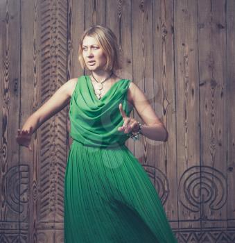 Torso shot toned image romantic blond hair women in long green dress on the background of ancient wood door art posing
