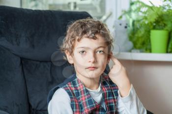 boy looking at camera with blank expression on the face. Indoor shot