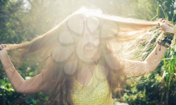 Portrait of happy woman with hand in hair against nature background