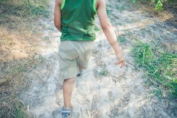 Boy walking in a fores alone. Part of a body shot