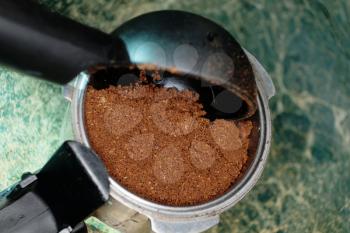 Adding Ground coffee in portafilter with plastic spoon macro image