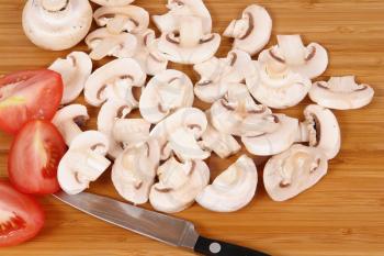 Royalty Free Photo of Mushrooms and Tomatoes on a Cutting Board