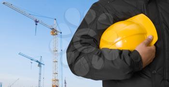 Royalty Free Photo of a Builder Holding a Yellow Hardhat 