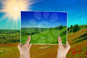 Royalty Free Photo of Hands Holding a Photo of a Hilly Landscape