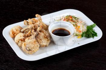 Fried chicken wings garnished with fresh vegetables with Teriyaki sauce