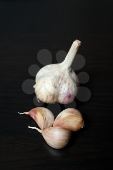 plait of garlic bulbs close-up on black background