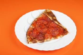 Pancake with red caviar on orange background