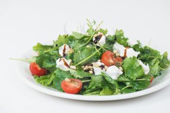 Green salad with vegetables: greens, arugula, tomato, cheese pine nuts and sauce