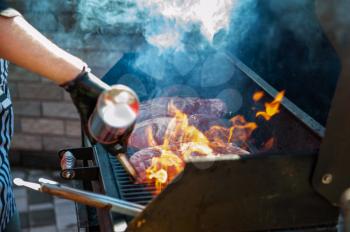 A professional cook prepares meat on the grill outdoor, food or catering concept