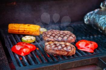 Beef steaks with vegetables on the grill with flames
