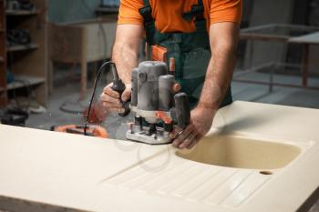 Stone sink furniture production. Carpenter polishes the surface of the sink with a grinder