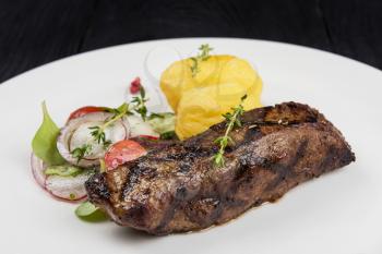 Grilled beef meat with potato and vegetables on white plate
