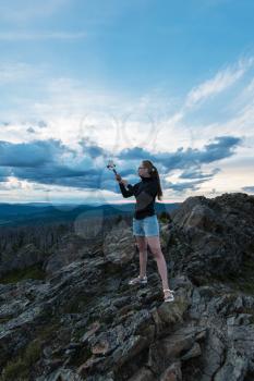 Travel, lesure and freedom concept - woman on the top of Altai mountain, making selfie on beauty summer evening landcape