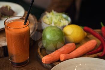 Healthy vegeterian food on brown wood board. Spring vitamin dieting food. Fruit and raw vagetables and carrot juice